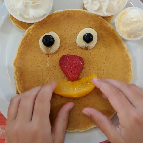 Iden Elliott adjusts a smiley face on pancakes at...