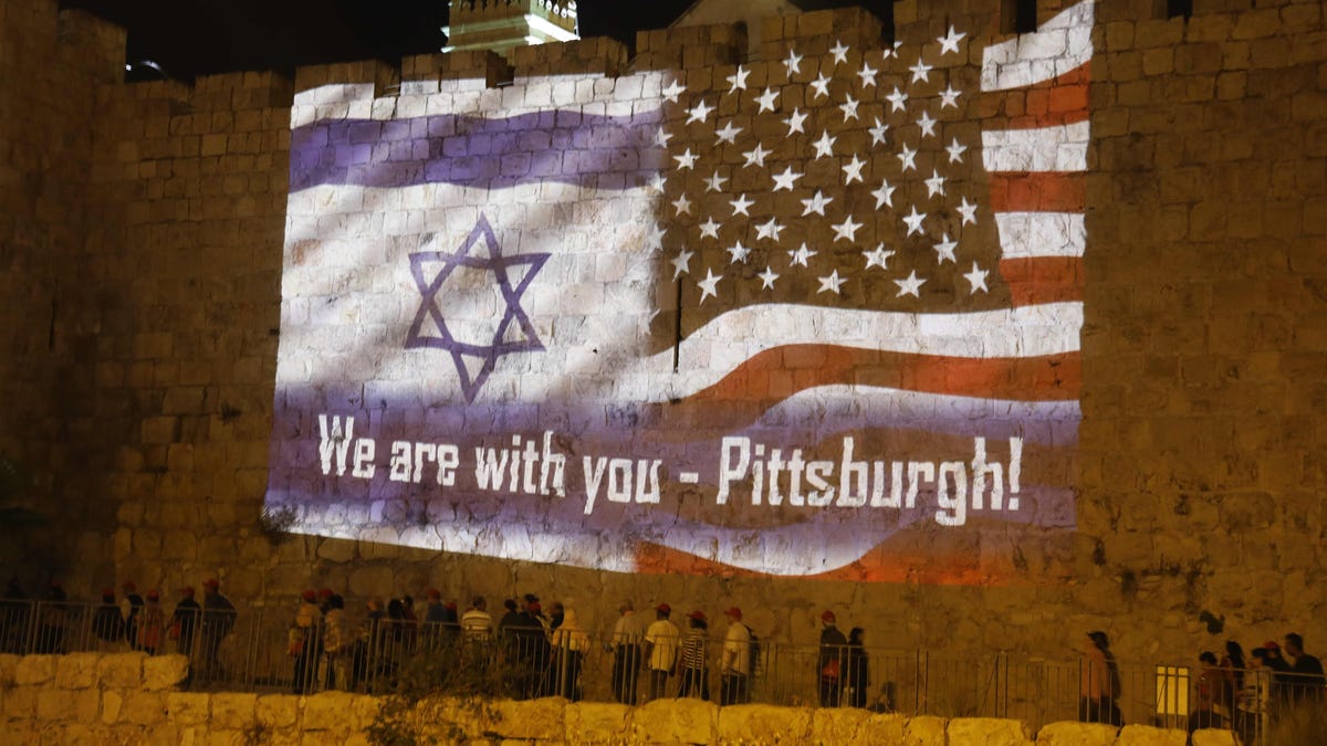 People gather under the US and the Israeli flags projected on the walls of Jerusalem old city on October 28, 2018, organised by Jerusalem municipality to show solidarity with the Pittsburgh Jewish community following the shooting attack at the Tree of Life synagogue in Pittsburgh, Pennsylvania.