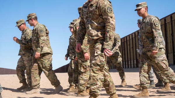 National Guard troops in San Luis, Ariz., walk...