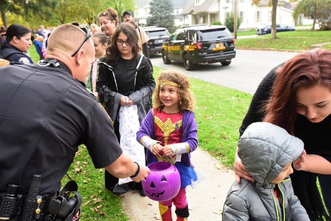Deputy Gary Pollock of the Sandusky County Sheriff's Office gives candy to Ana'Leigh Sims, 5, of Fremont during Candy with the Cops at Birchard Park on Tuesday evening.