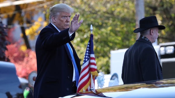 Trump waves after placing stones and flowers on a...