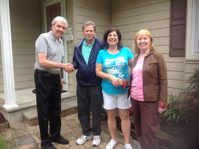 First-time homebuyers Rupert and Pat Haller (couple on the outside) shake hands with the sellers, Bob and Ellen Donnell (couple on the inside).