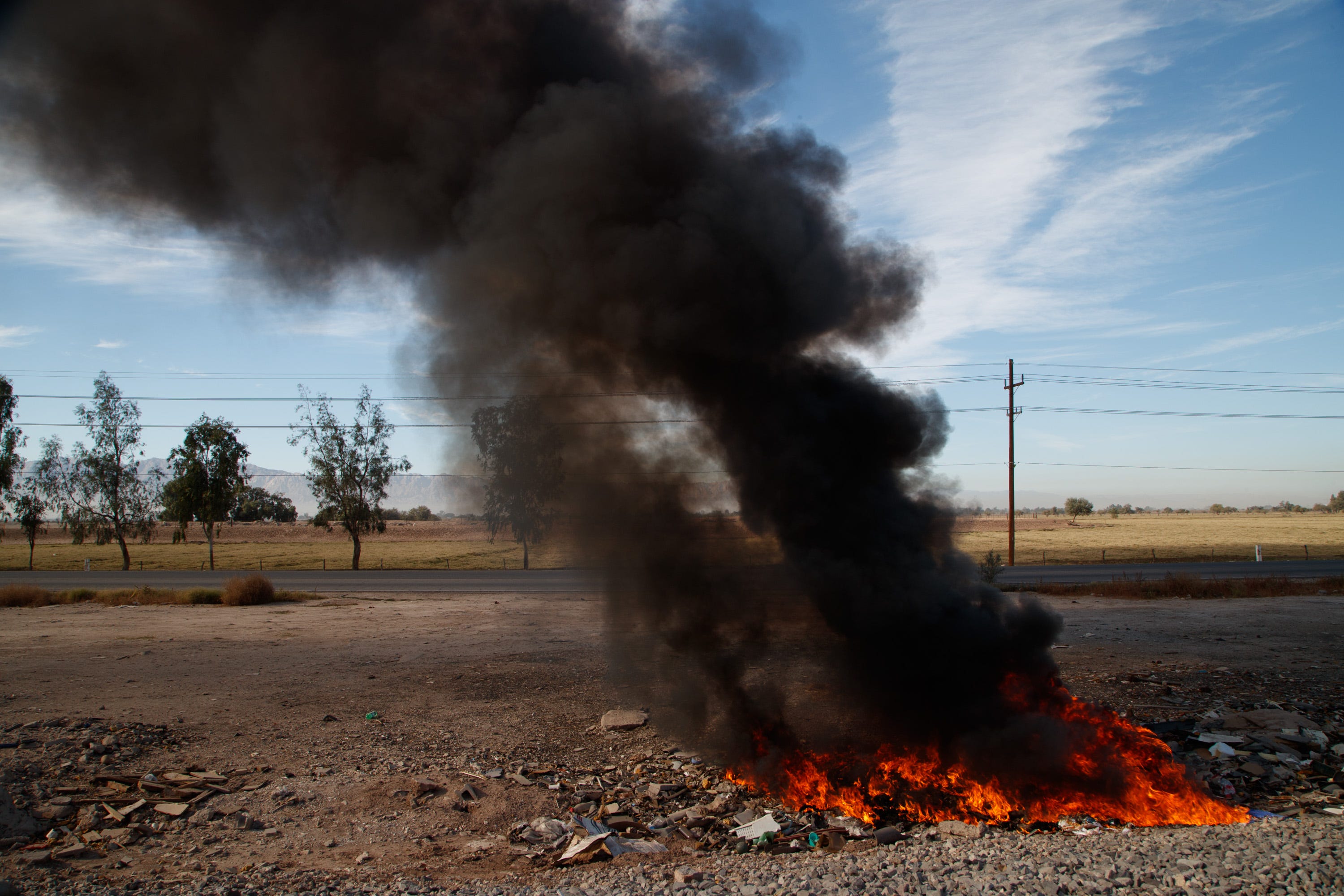 Black smoke billows from a blazing pile of trash in the countryside near Mexicali.