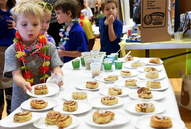 Tanner Avera grabs a cinnamon roll off the table during the multi-cultural market at Community Montessori, Wednesday, October 31.