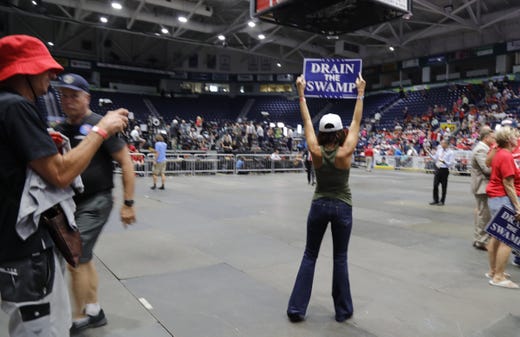 Brittany Webb, of Marco Island, displays a âDrain The Swampâ sign for the crowd coming into Hertz Arena Wednesday afternoon as part of the Make America Great Again rally.