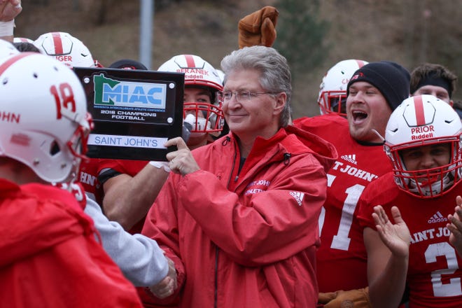 St. John's University president, Michael Hemesath, presents the football team with the MIAC championship trophy after the Johnnies beat Hamline 51-0 Saturday in Collegeville.
