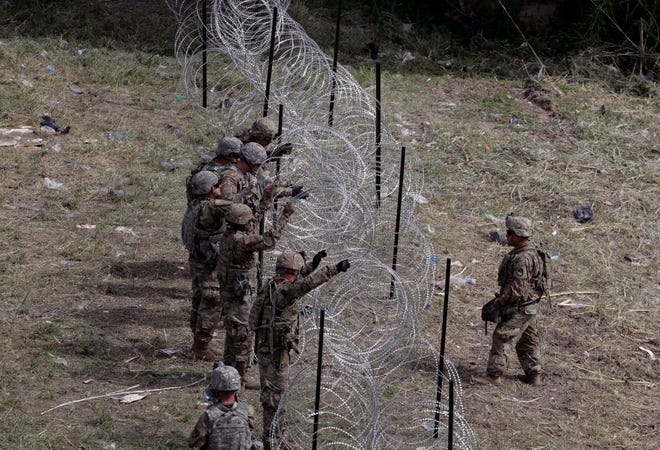 Members of the U.S.military place razor wire along the U.S.-Mexico border near the McAllen-Hidalgo International Bridge on Friday in McAllen, Texas.