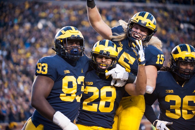 Michigan defensive back Brandon Watson (28) is mobbed in celebration by his teammates Lawrence Marshall (93), Chase Winovich (15) and Devin Gil (36) after he intercepted a pass and returned it 62 yards for a touchdown in the third quarter. The Wolverines' 42-7 victory over the Nittany Lions avenged a 42-13 loss at Penn State last year.