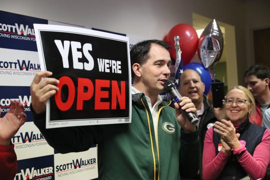 Gov. Scott Walker holds up a sign to tout his record on job creation.