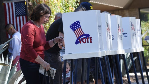 People vote at outdoor booths during early voting...