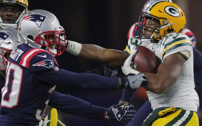Green Bay Packers running back Aaron Jones (33) is tackled by New England Patriots cornerback Jason McCourty (30) after a short gain during the second quarter of their game Sunday, November 4, 2018 at Gillette Stadium in Foxborough, Mass.