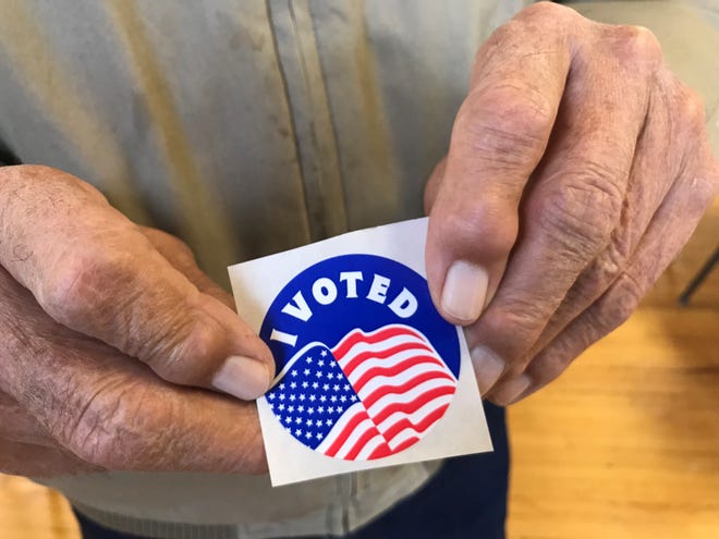Vern Kuka holds his “I Voted” sticker in Valier after voting with his wife Marie.