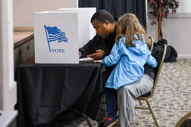 Cameron Ball votes in the midterm election with his daughter on his lap at the Wicomico Civic Center on Tuesday, Nov 6, 2018.