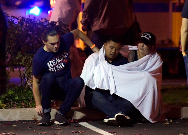 People comfort each other as they sit near the scene Thursday in Thousand Oaks where a gunman opened fire Wednesday inside the Borderline Bar & Grill that was crowded with hundreds of people.