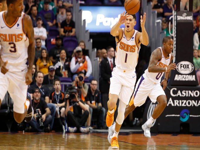 Suns' Devin Booker (1) passes the ball up court to teammate Trevor Ariza (3) against the Celtics during the first half at Talking Stick Resort Arena in Phoenix, Ariz. on November 8, 2018. 