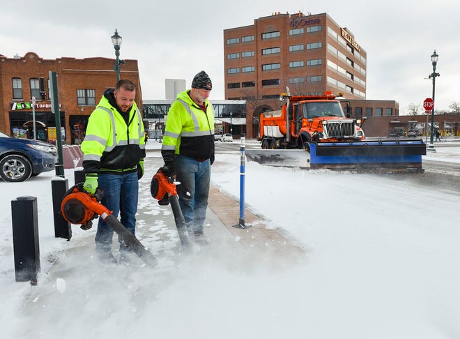 Justin Mrosla and Brian Primus, St. Cloud Public Works, clear the light snow off the sidewalks Friday, Nov. 9, along First Street South downtown St. Cloud.