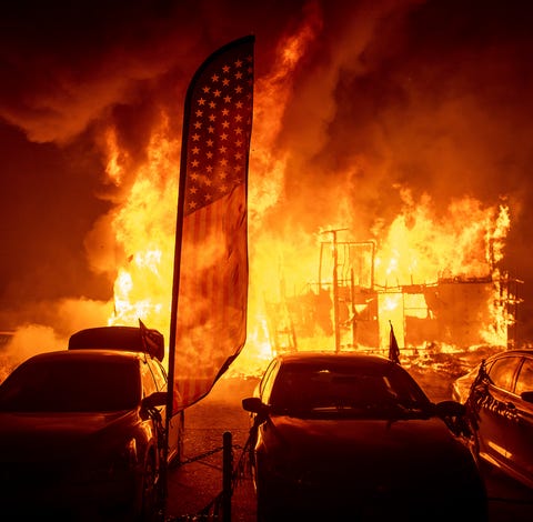 Flames consume a car dealership as the Camp Fire...