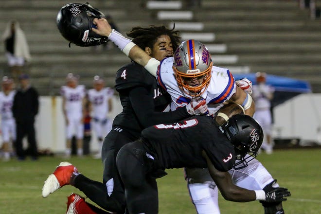 West Florida Tech's Antarrius Moultrie (4) has his helmet ripped off by Jacksonville Bolles' CJ Grimes (22) as teammate Keyshawn Swanson (3) comes in to help with the tackle in the Region 1-5A quarterfinal game at Woodham Middle School on Friday, November 9, 2018.