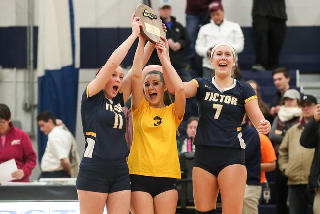 Victor captains Kate Simplicio (11), Ally McFadden (3), and Makenzie Bills (7) hold up their trophy after defeating Orchard Park in the Class AA West Regional high school girls volleyball match at Webster Thomas on Nov. 9, 2018.