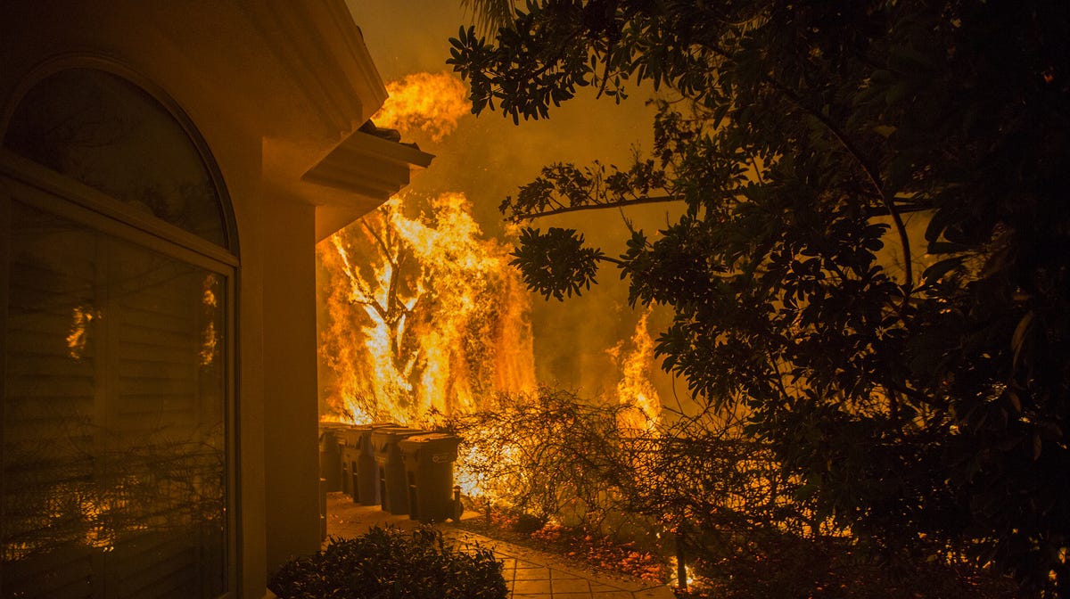 Flames approach a house, Friday with a loud roaring sound, during the Woolsey Fire on in Malibu, Calif.