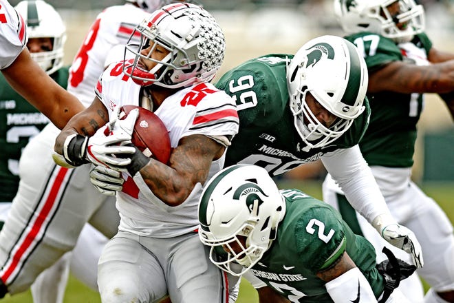 Michigan State's Raequan Williams, right, and Justin Layne, bottom, tackle Ohio State's Mike Weber Jr. during the first quarter on Saturday, Nov. 10, 2018, in East Lansing.