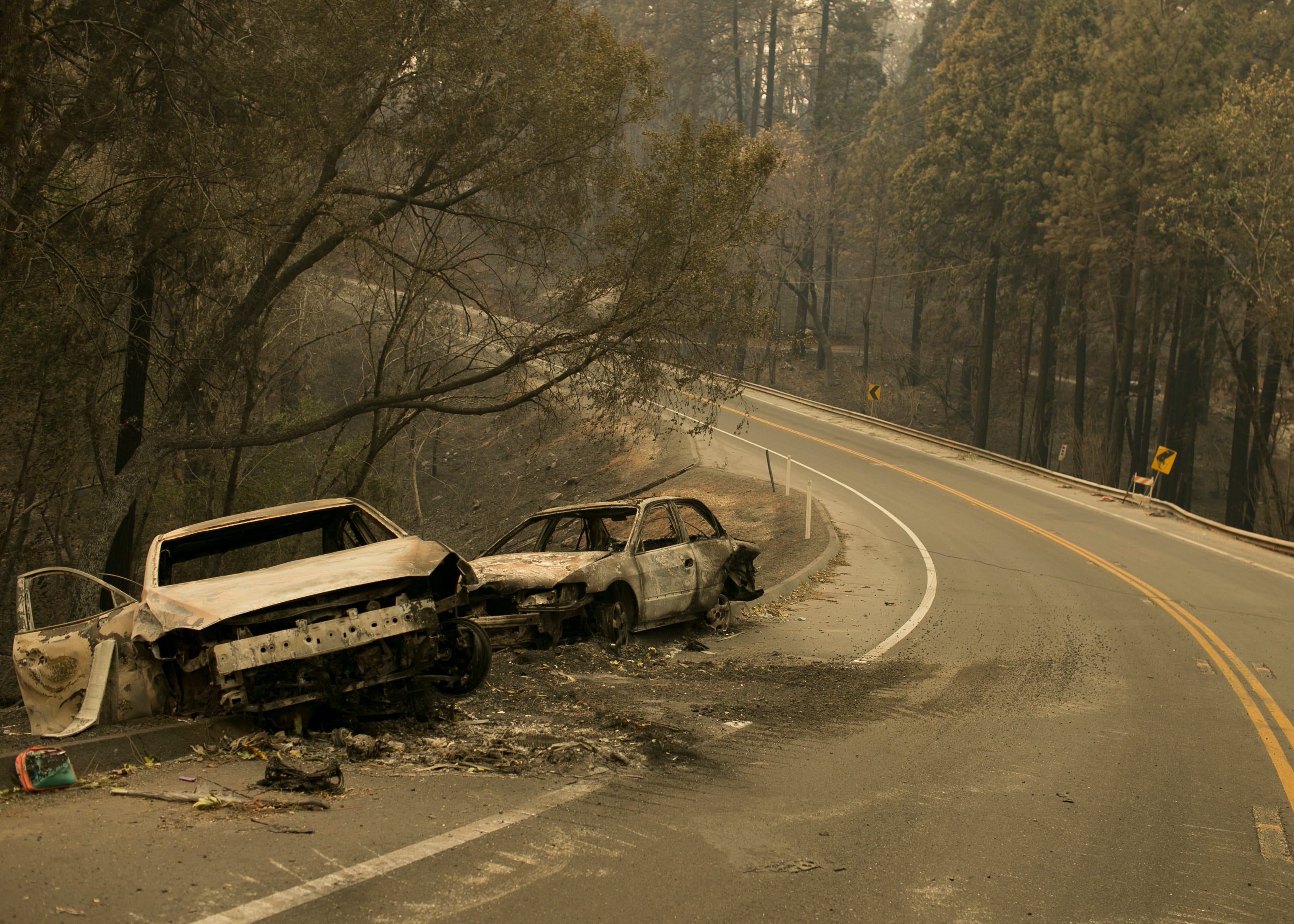 Vehicles sit pushed off the road days after the Camp Fire swept through town on Nov. 8 in Paradise.