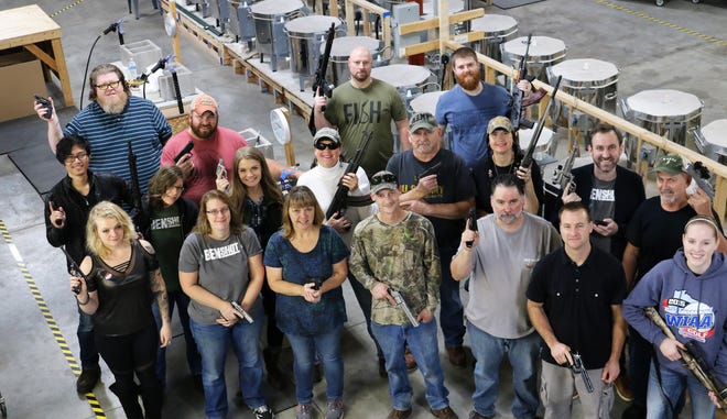 Employees at BenShot, a business that produces glassware embedded with bullets, show off their guns at their workshop in Hortonville. Each employee was given a handgun as a Christmas gift from the business.