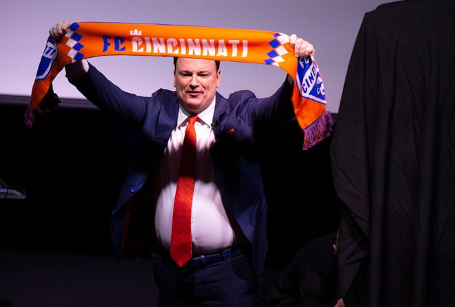 General manager Jeff Berding raises a newly branded scarf during an event to unveil FC Cincinnati's new MLS branding at the Woodward Theater in the Over-the-Rhine neighborhood of Cincinnati on Monday, Nov. 12, 2018.