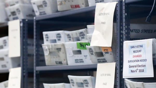Bins filled with ballots are stacked at the...