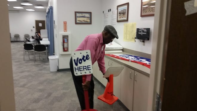 Poll worker Lawrence Kenniebrew takes in the "vote here" signs at Thomas Branigan Memorial Library on election night, Tuesday, Nov. 6, 2018 after the close of the polling site.