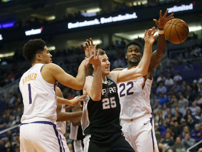 Phoenix Suns guard Devin Booker (1) and center Deandre Ayton (22) battle San Antonio Spurs center Jakob Poeltl (25) for the ball during a NBA game at Talking Stick Arena in Phoenix on November 14.
