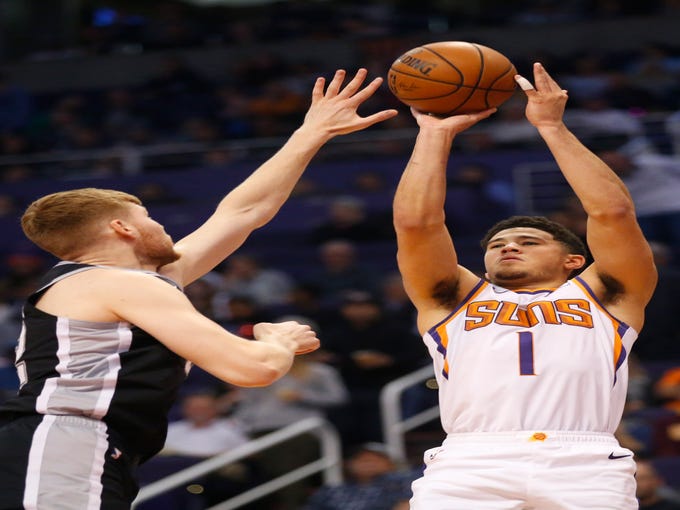 Phoenix Suns guard Devin Booker (1) takes a shot while being guarded by San Antonio Spurs forward Davis Bertans (42) during a NBA game at Talking Stick Arena in Phoenix on November 14.  