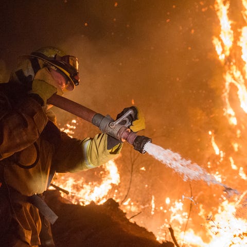Firefighters work to control the Camp Fire north...