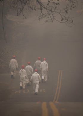 Search and rescue personnel walk to their next destination to comb through debris searching for remains in a neighborhood near Pentz Road in Paradise, CA, after the Camp Fire devastated the area.