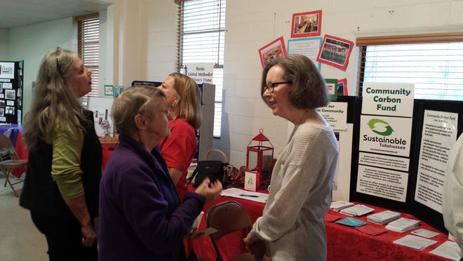 Debbie Gibson, left, and Pamela McVety with visitors at the Alternative Christmas Market Carbon Fund booth.