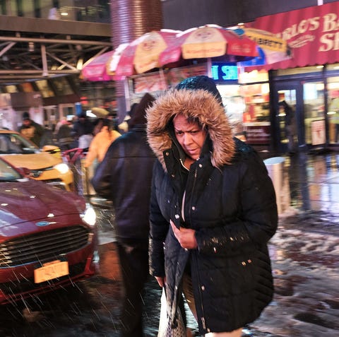 Pedestrians walk through a wintery mix of snow,...