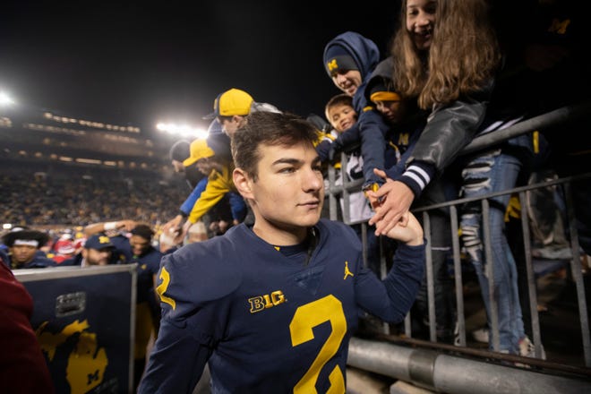 Michigan place kicker Jake Moody high-fives the fans after the game.