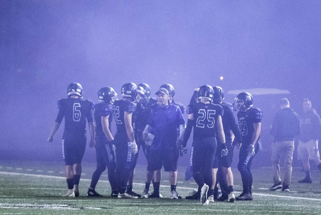 Under a cloud of smoke Northwest Christian coach David InnessÊrallies his players before their game with Valley Christian at North Canyon High School in Phoenix  Friday, Nov.17, 2018. #azhsfb