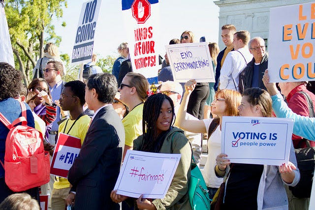 Demonstrators affiliated with the League of Women Voters advocate for redistricting reform and fair maps.