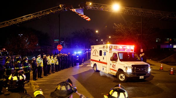 Police and firefighters salute as an ambulance...