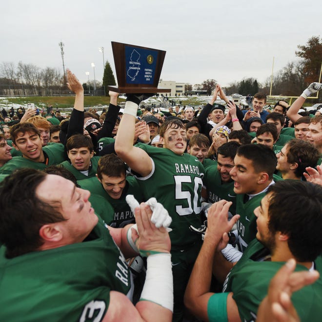 Sean Costello (no. 50) holds up the Championship Plaque as  Ramapo players celebrate their championship victory 31 to 7 over River Dell in the second half during the North 1, Group 3 football final at Ramapo High School in Franklin Lakes on 11/18/18. (Mitsu Yasukawa/@mitsuyasukawa)