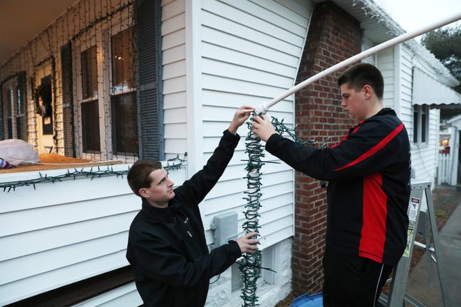 Austin Lemmon, 14, right, and his brother Brandon, 17, hang lights for their Christmas light show at their Lindbergh Avenue home.