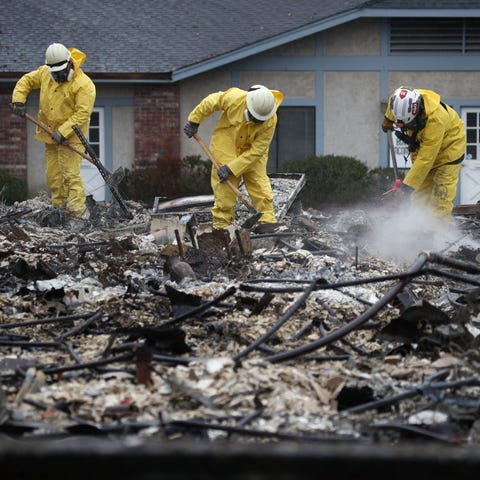 Search and rescue crews dig through the burnt...
