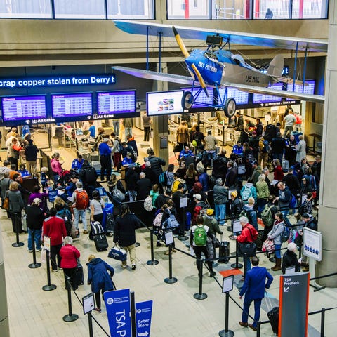 Travelers wait in security lines at the...
