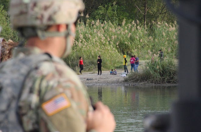 A soldier from the Kentucky-based 19th Engineer Battalion looks across the Rio Grande River from Laredo, Texas, into Nuevo Laredo, Mexico, where a group of people hang out on the river bank on Nov. 17, 2018.