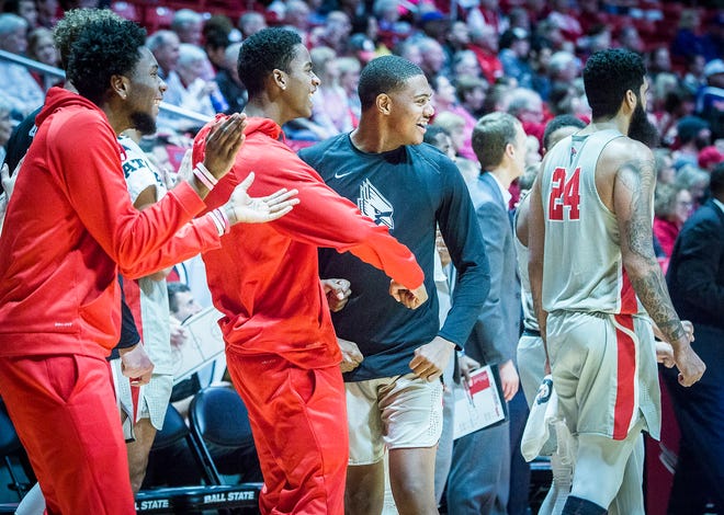 Ball State players Kani Acree (left), Miryne Thomas (center) and Jarron Coleman cheer on their teammates during a game against Evansville at Worthen Arena Saturday, Nov. 24, 2018.