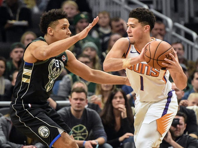 Suns guard Devin Booker is defended by Bucks guard Malcolm Brogdon during the first quarter of a game Nov. 23 in Milwaukee.