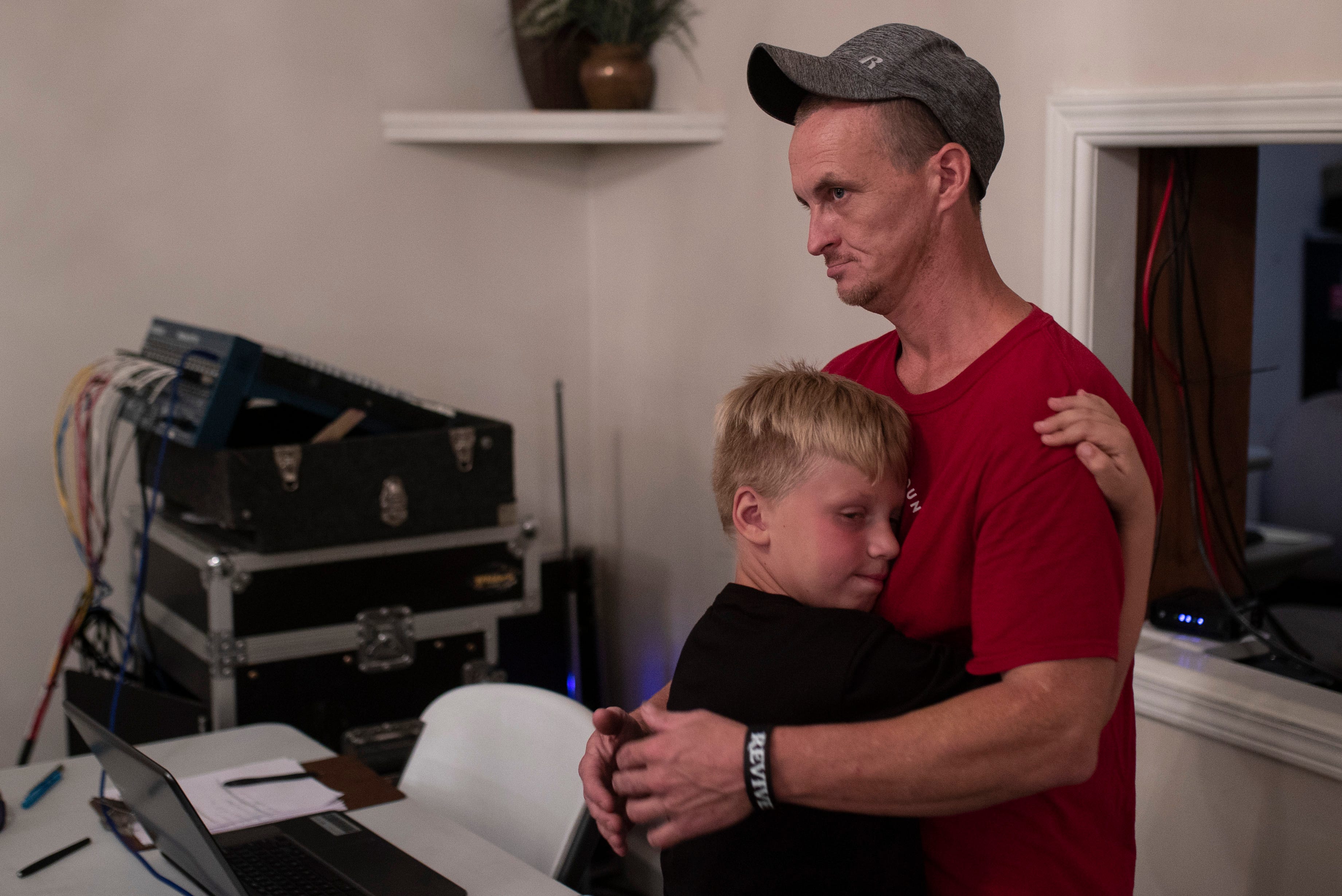 Howell, right, gets a hug from his son Colten Coomer, 9, during a late night at the church where Jacob filled in as the sound man for the choir. Sept. 12, 2018