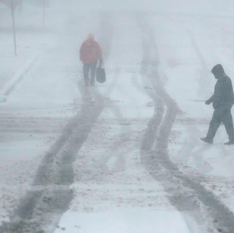 Pedestrians walk along a snow-covered street...