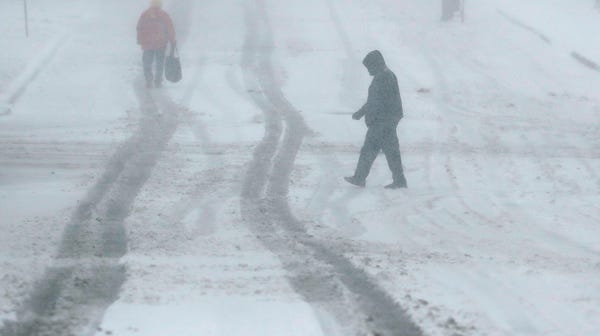 Pedestrians walk along a snow-covered street...